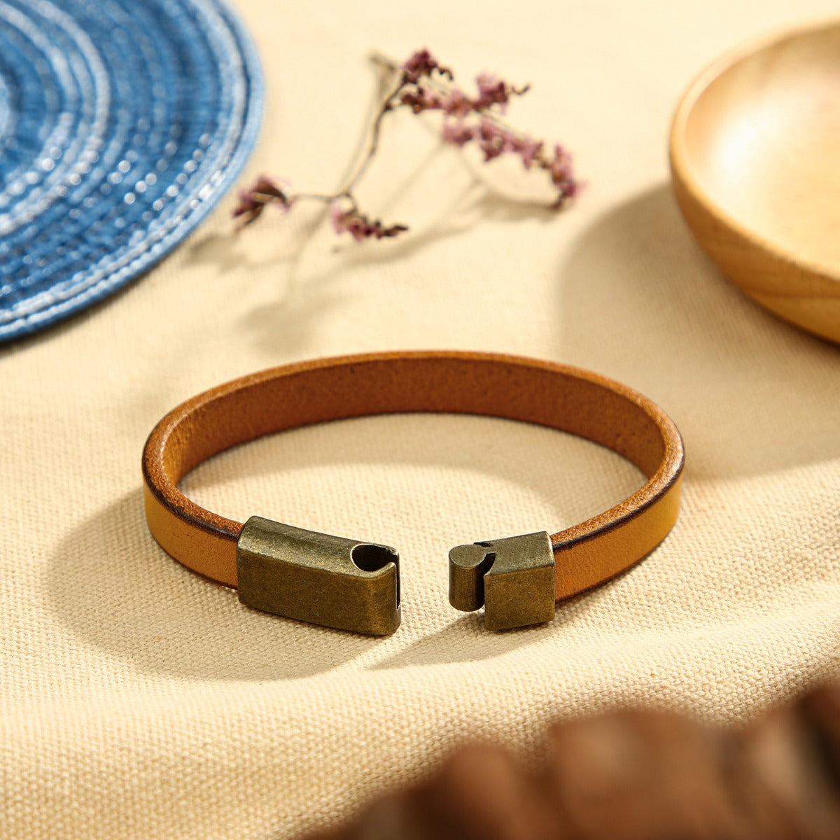 name necklace , Brown leather personalized bracelet with metallic clasp on beige fabric surface