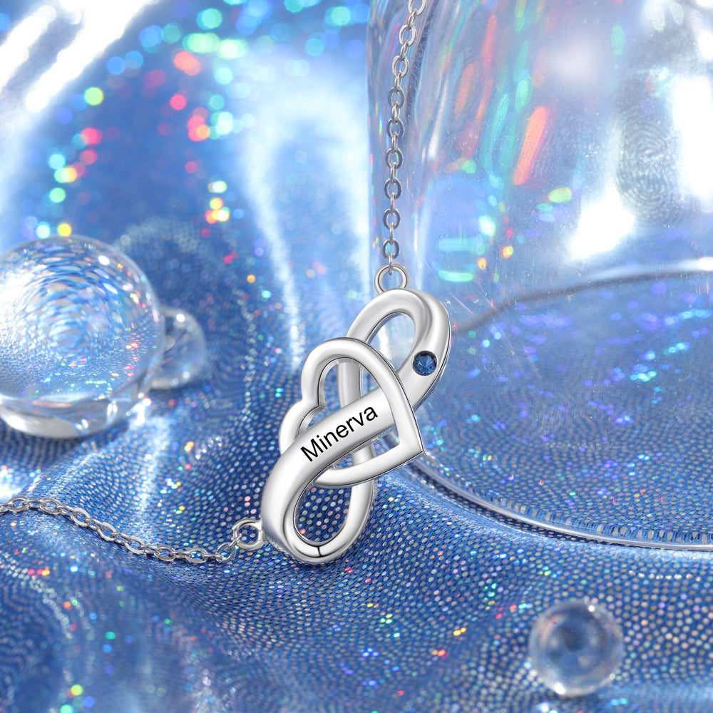 Custom Birthstone Infinity Necklace on glittery blue fabric with engraved "Minerva" pendant