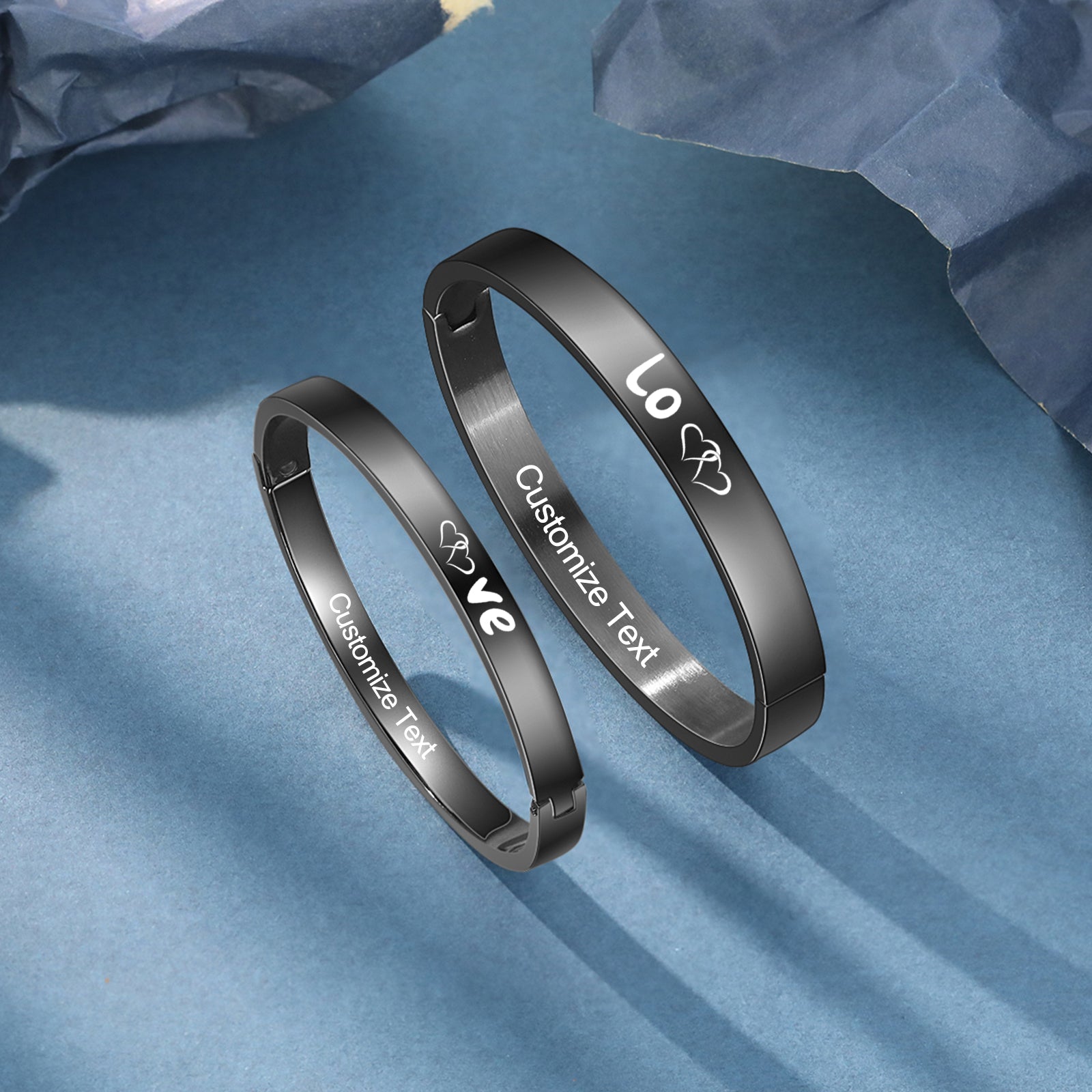 Couple bracelet pair with "Love" engraving on blue surface, ring sound theme.