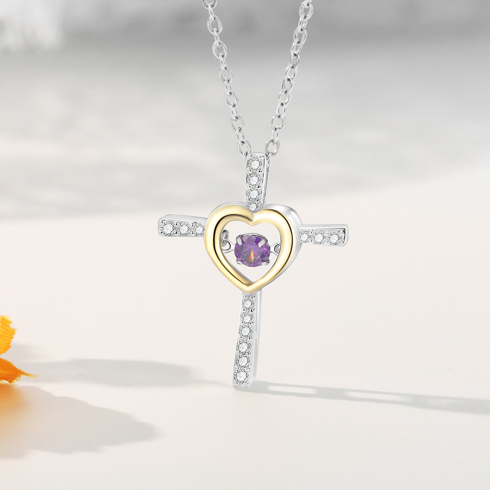 Silver and gold cross heart necklace with purple gemstone on white background