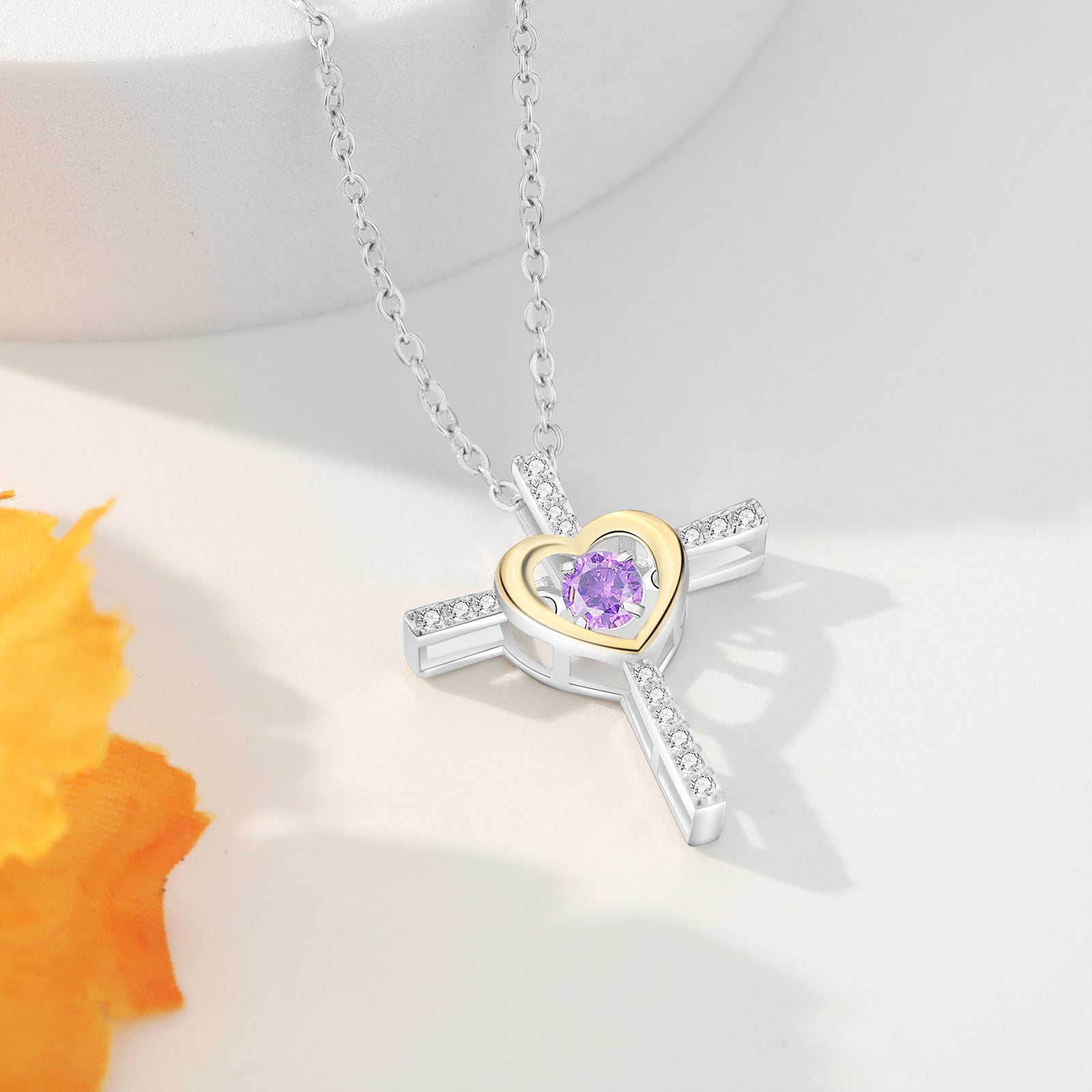 name bracelet, heart-shaped necklace with purple gemstone amid blurred orange flower backdrop