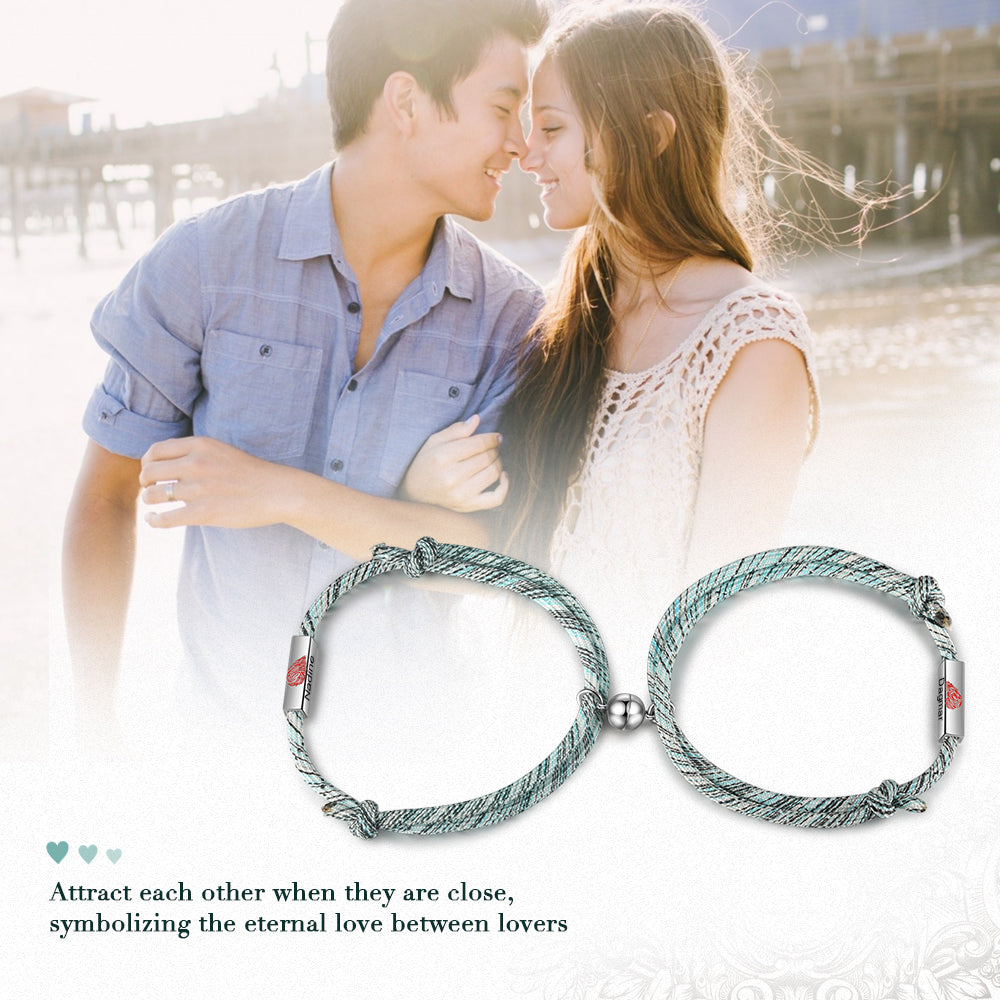 Couple bracelet with silver keychains on beach, symbolizing love and connection