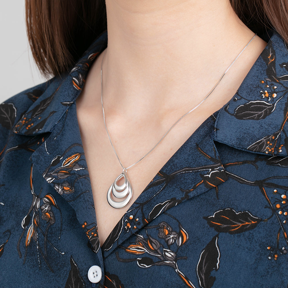 Custom Circle Necklace with silver teardrop pendant on floral blue shirt