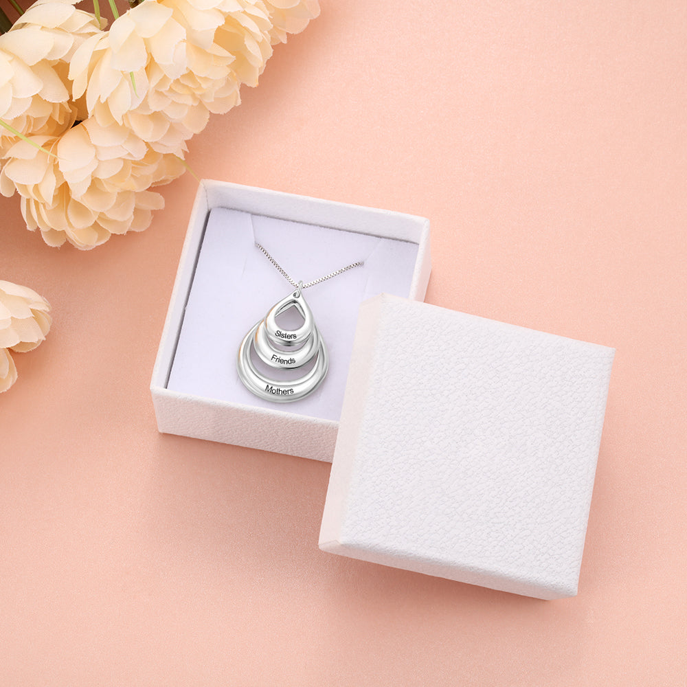 Custom Circle Necklace with three inscribed silver circles in a white box on pink surface