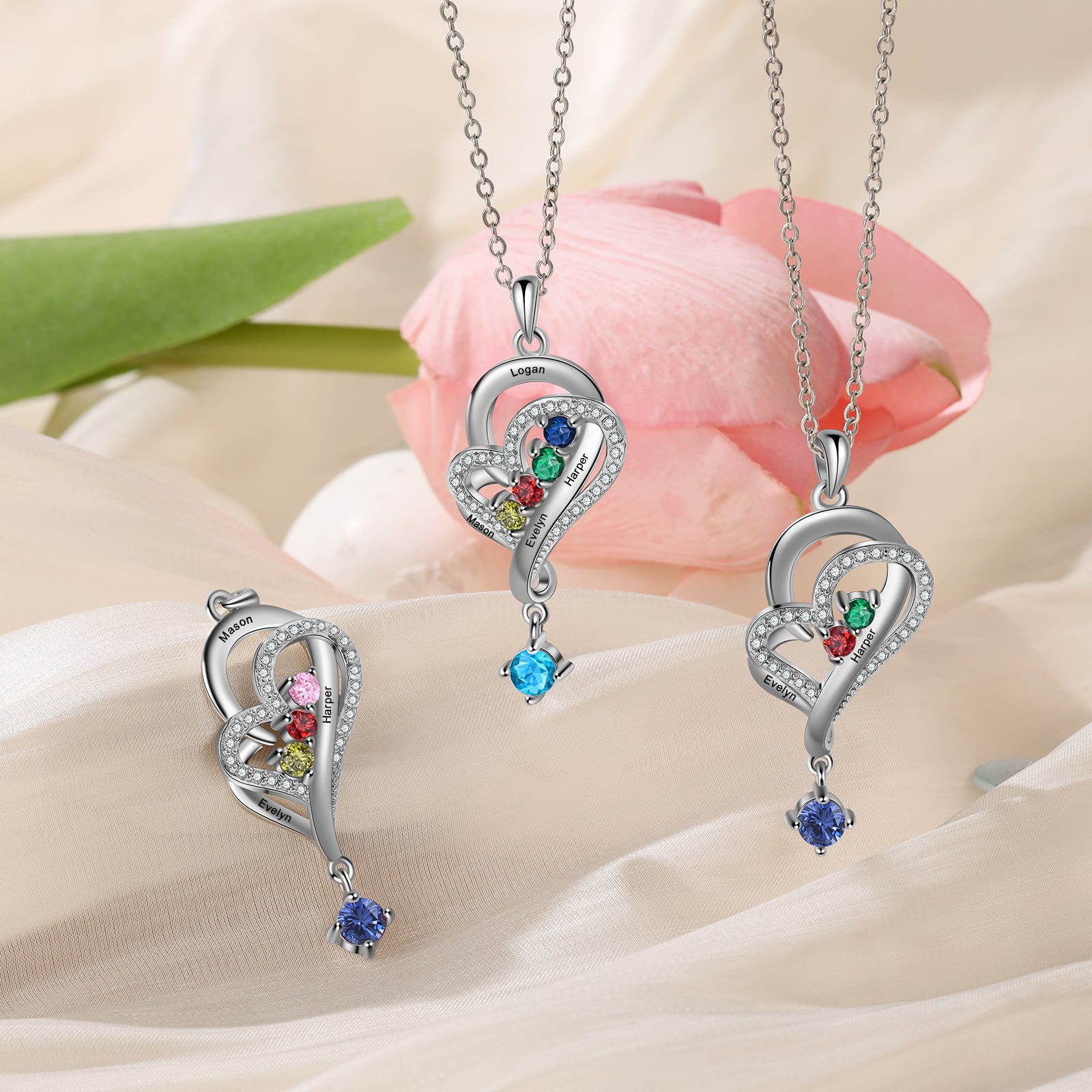 ring sound, Silver heart pendants with gemstones on pink fabric, personalized jewelry display.