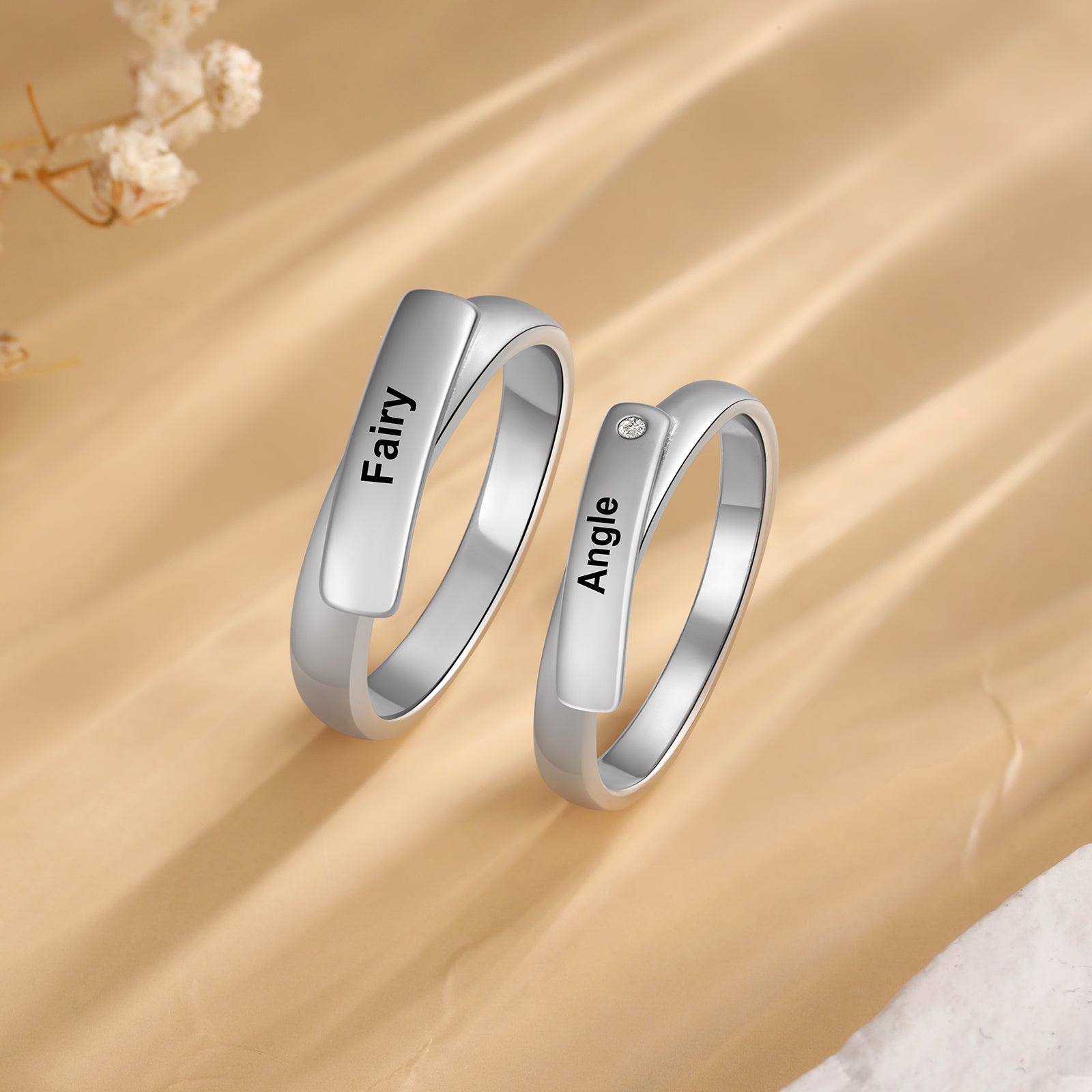 name ring, Custom couple rings with inscriptions "Fairy" and "Angle" on beige surface.